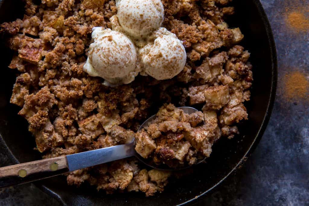 A cozy wooden handled serving spoon scooping apple crisp