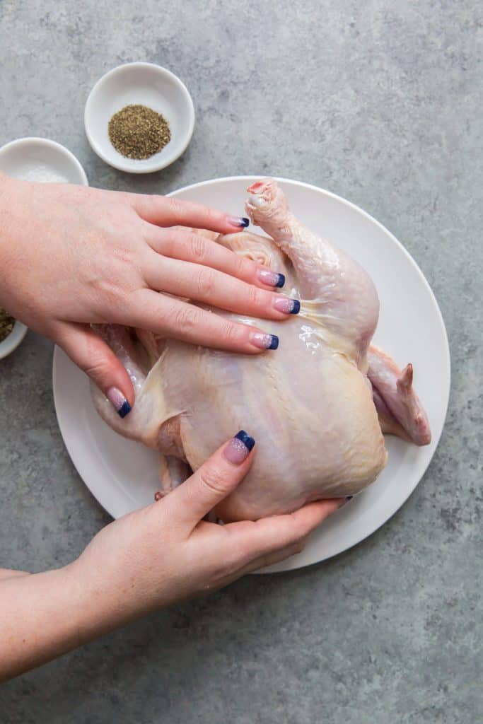 Air Fryer Whole Chicken hand massaging in avocado oil on a whole chicken