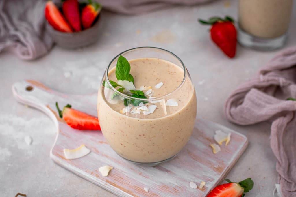 keto strawberry smoothie a small clear glass of strawberry smoothie on a cutting board