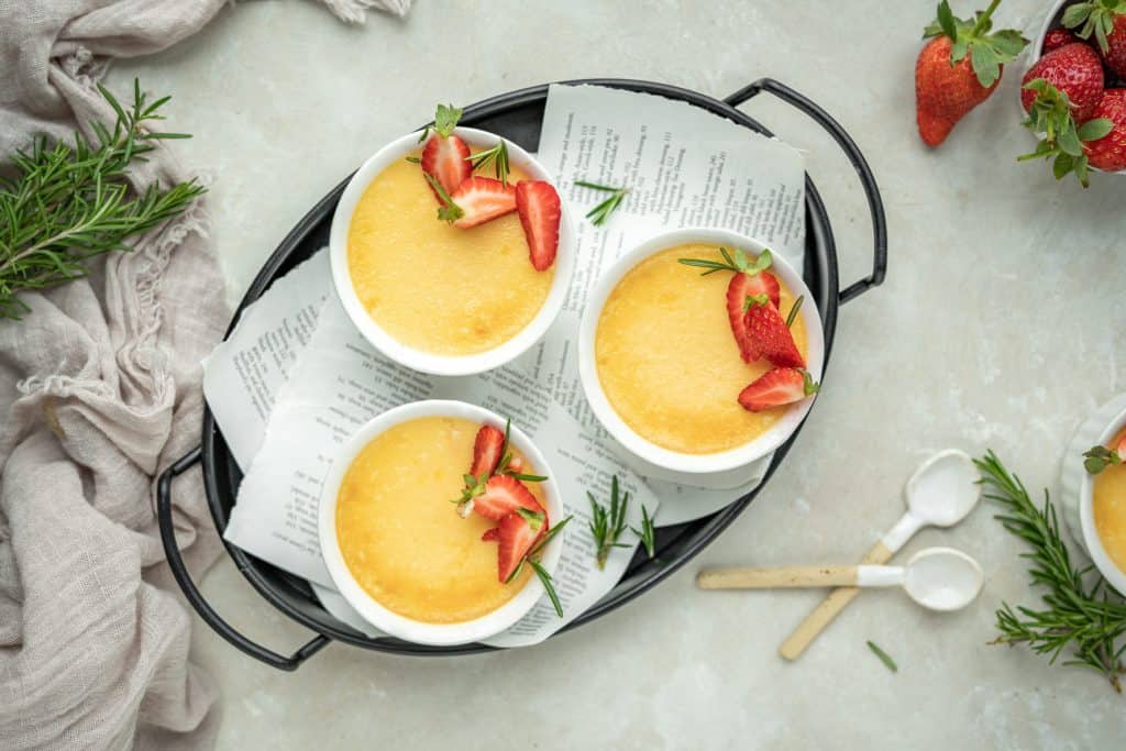 Keto custard surrounded by rosemary, berries, and wooden spoons