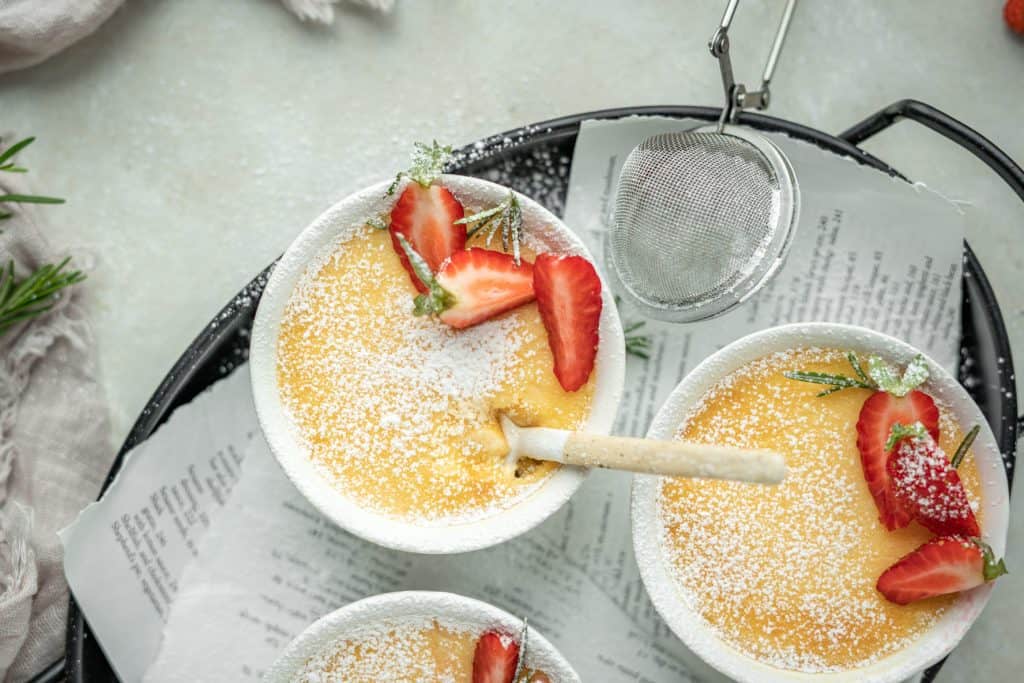 Keto Custard tea tray with keto custards, wooden spoons, and chopped strawberries