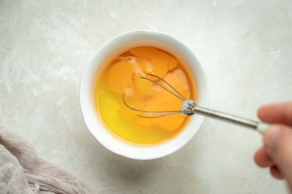 a small sliver whisk mixing two eggs