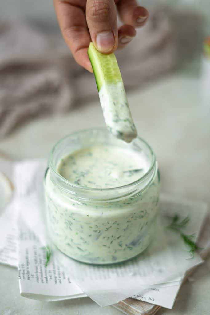 A cucumber being dipped into homemade ranch