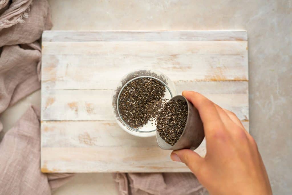 keto chia pudding Adding Chia Seeds to mason jar.