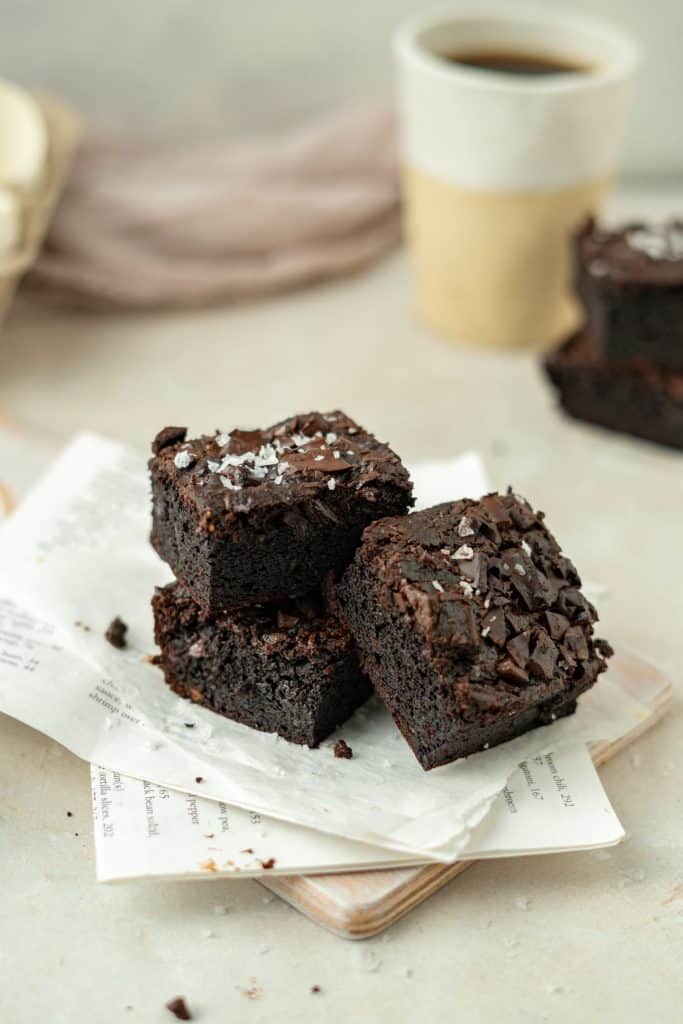Keto Avocado Brownies Three brownies leaning on one another a top newspaper.
