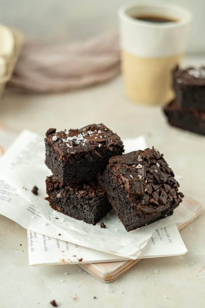 Three brownies leaning on one another a top newspaper. 