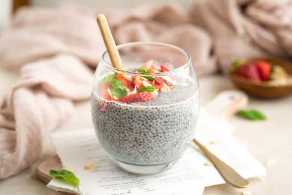 clear glass of chia pudding with strawberries and a spoon in