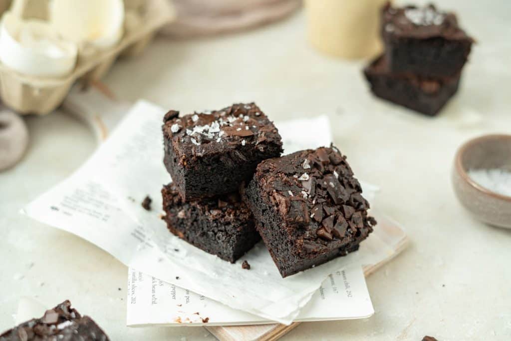 Keto Avocado Brownies Stacked and angled keto brownies a top newspaper.