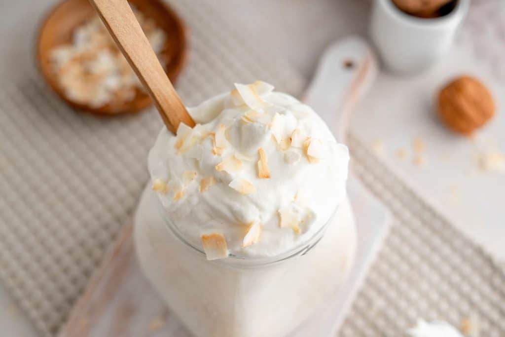 Fresh keto yogurt surrounded by coconut flakes and walnuts. 