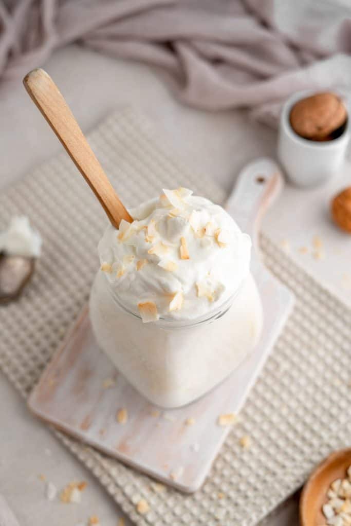 A wooden spoon resting in a jar of coconut yogurt