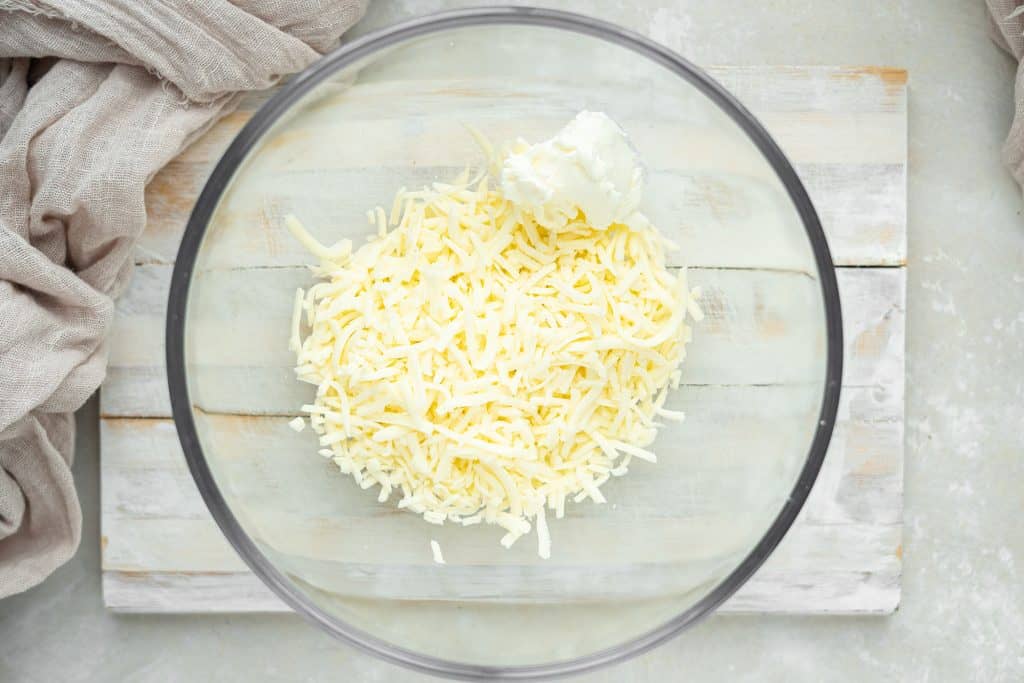 keto bagels mozzarella cheese and cream cheese in a clear glass mixing bowl