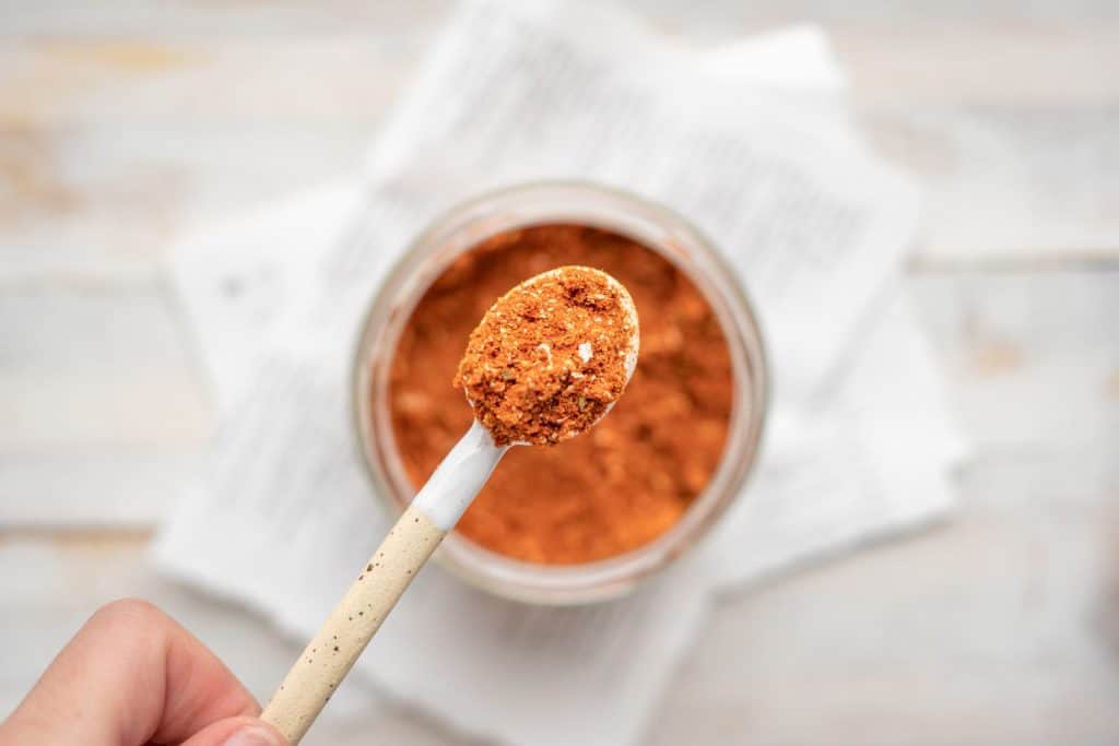 Keto taco seasoning A hand scooping a teaspoon of taco seasoning