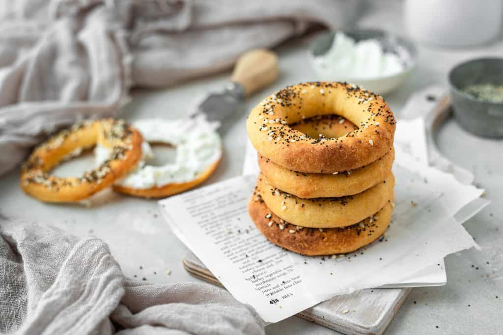 a stack of four keto bagels on a cutting board with cream cheese in the background
