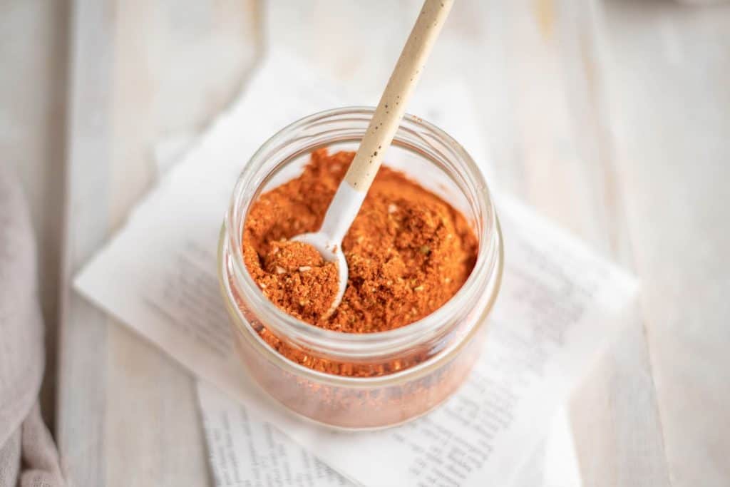 A jar of taco seasoning on top of newspaper