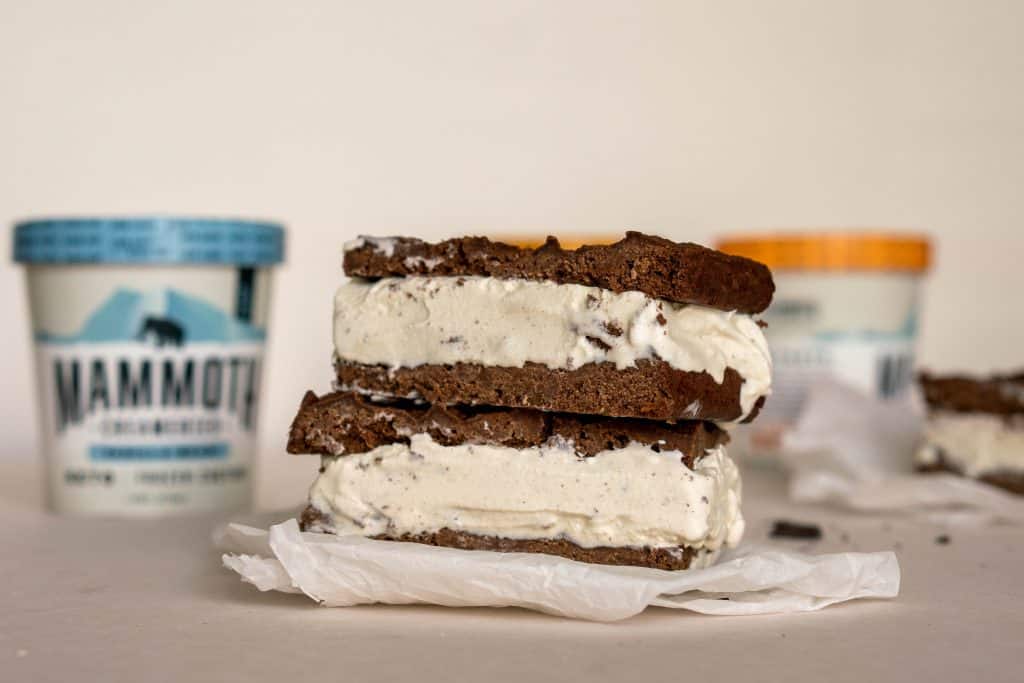 Keto Ice Cream Sandwich two ice cream sandwiches on top of each other with ice cream pints in the background