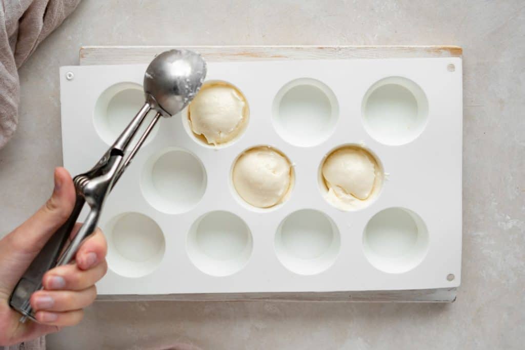 Keto Cheesecake Fat Bombs scooping cheesecake batter into cupcake molds