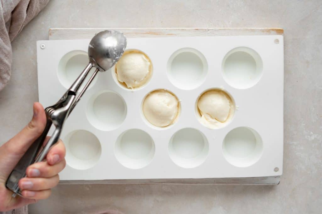 scooping cheesecake batter into cupcake molds