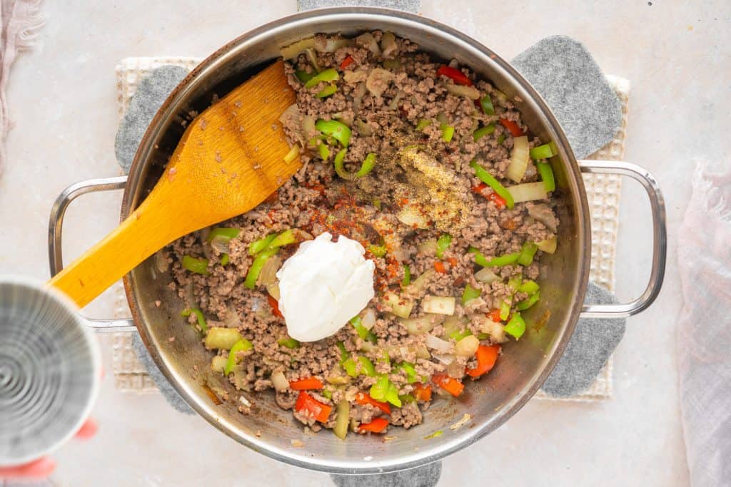 Philly cheesesteak casserole seasonings and cream cheese in ground beef