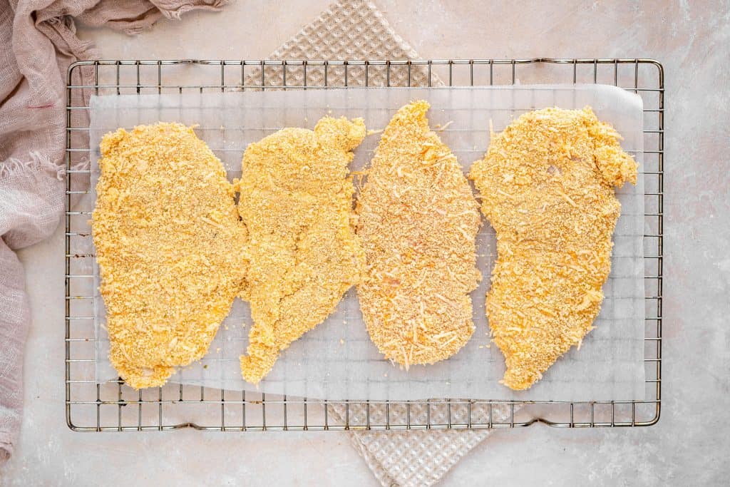keto chicken parmesan chicken breasts that have been breaded on a baking rack