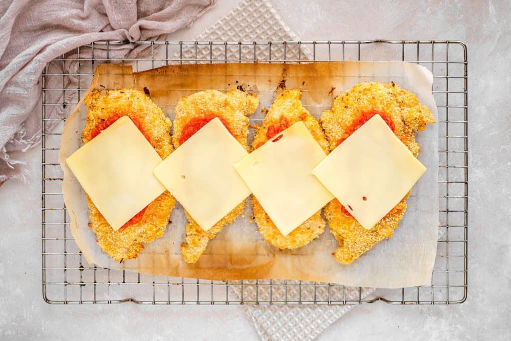 keto chicken parmesan adding cheese on top of the marinara sauce