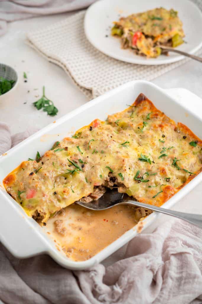 Philly cheesesteak casserole A soft pink hand towel next to a casserole dish of philly cheesesteak casserole