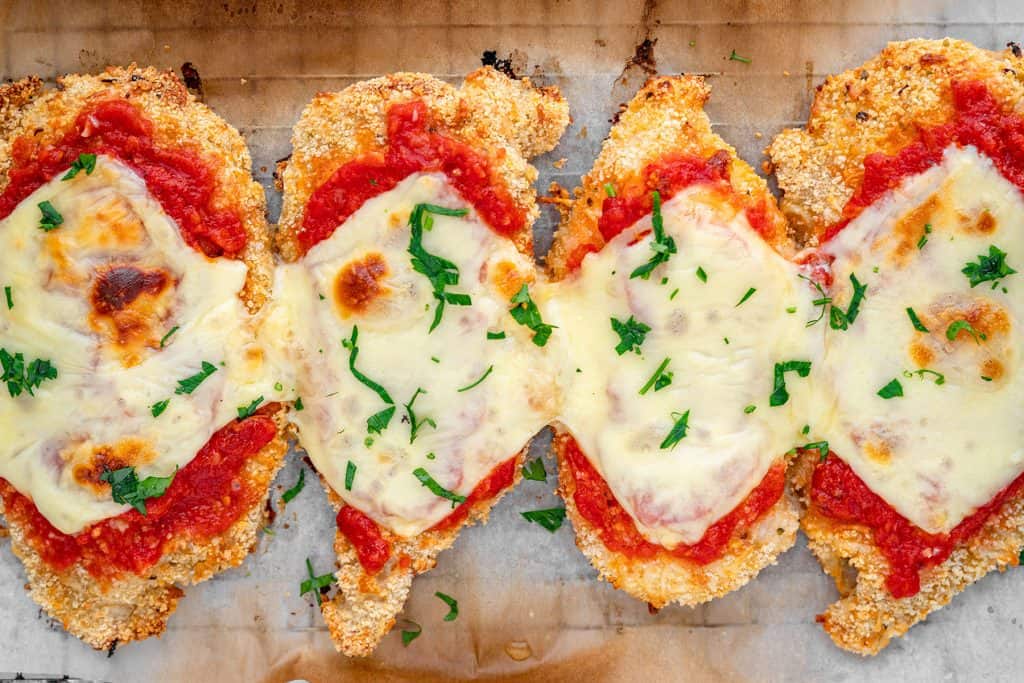 four pieces of chicken parmesan on parchment paper