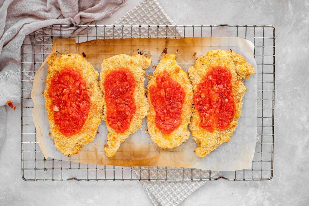 keto chicken parmesan adding marinara sauce to the chicken breasts once they have been baked