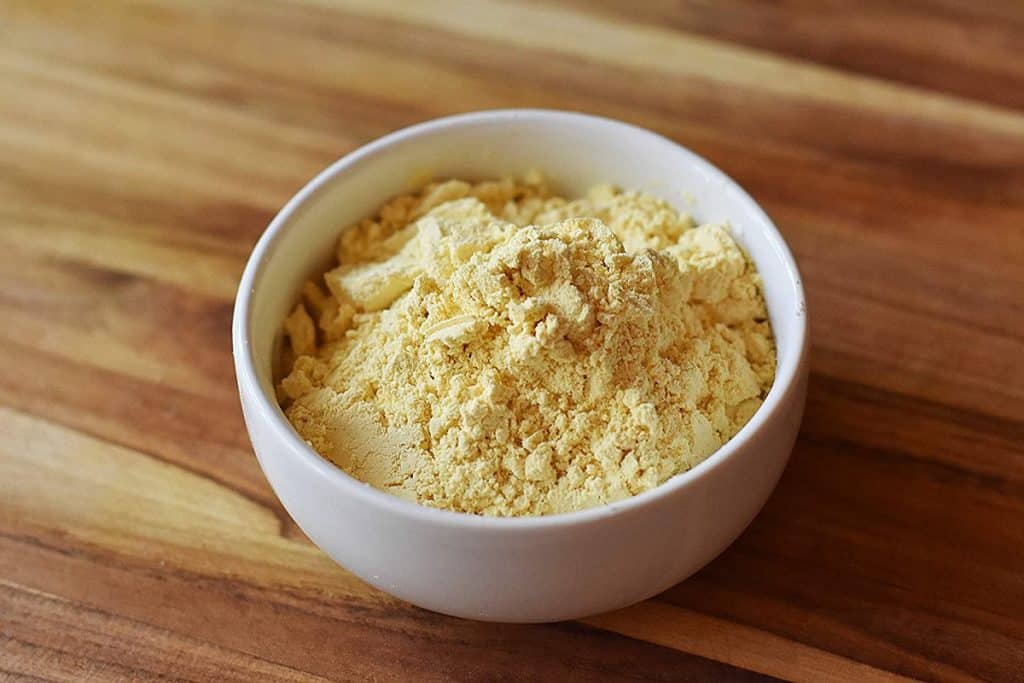 A white bowl filled with ground lupine flour on a wooden surface