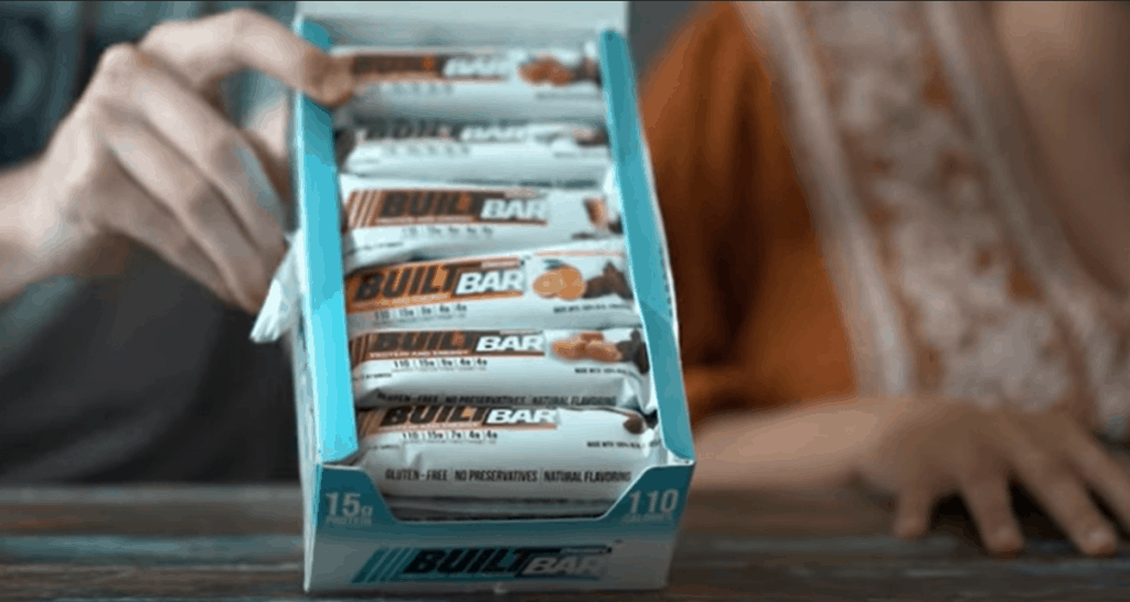 A package of several flavors of Built bars being held up at a 45 degree angle.