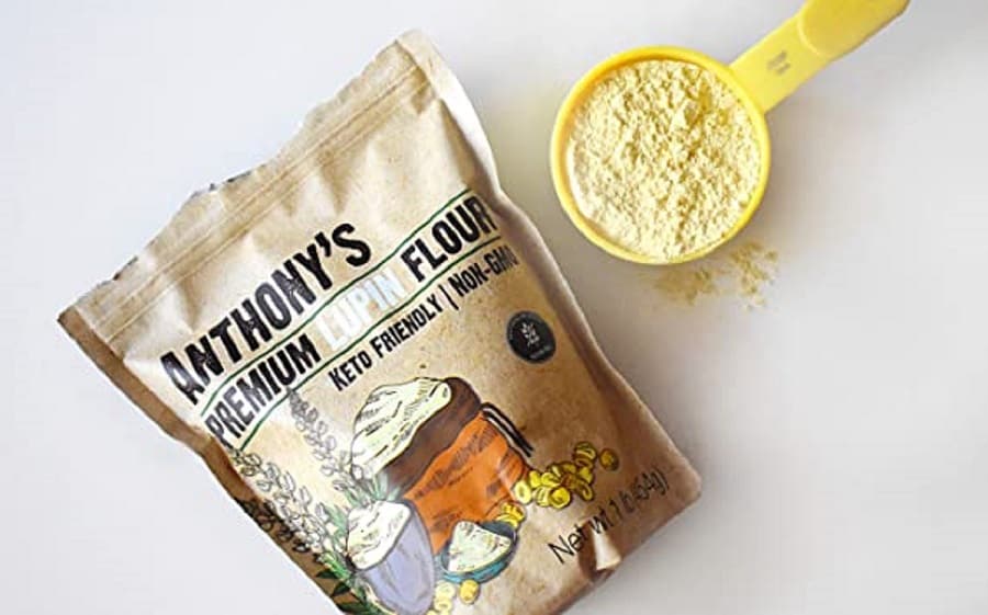 An overhead view of a bag of lupin flour and a measuring cup with ground lupin flour in it.