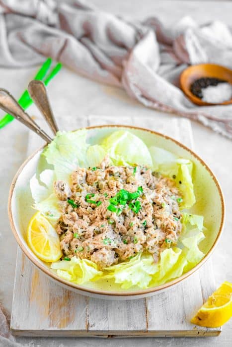 Angled shot of tuna salad in a bowl with romaine lettuce leaves under it.