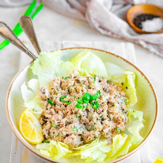 Angled shot of tuna salad in a bowl with romaine lettuce leaves under it.