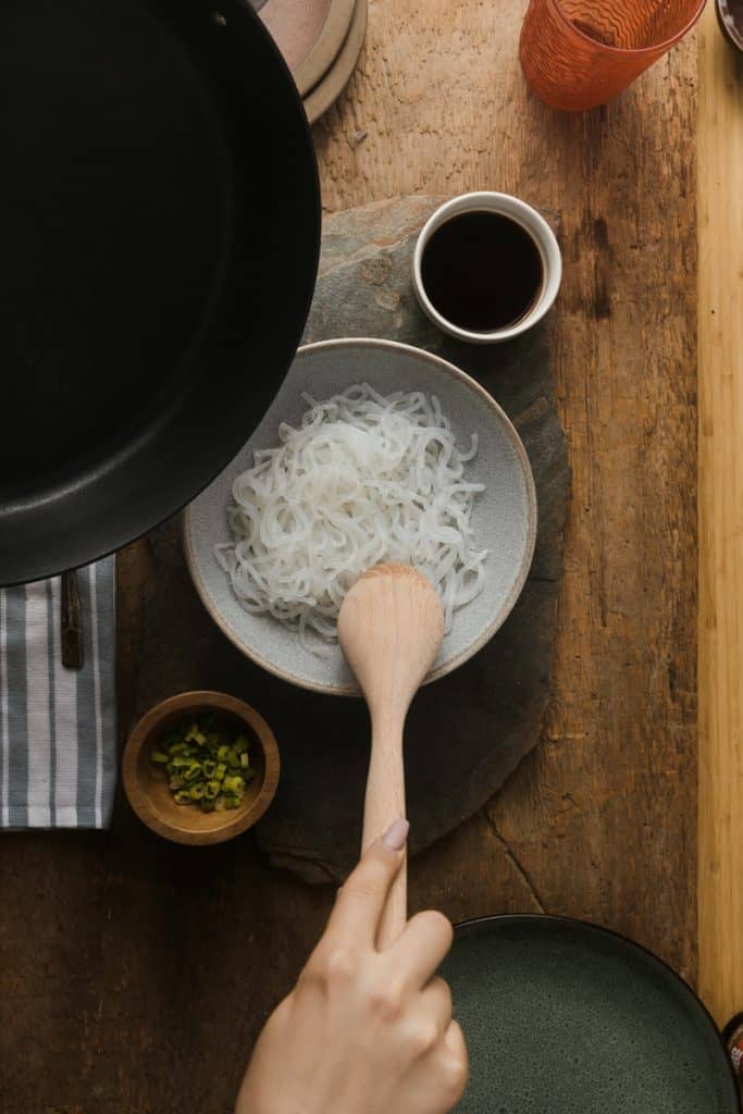Miracle Noodle Reviews Stirring miracle noodles in a bowl with a wooden spoon