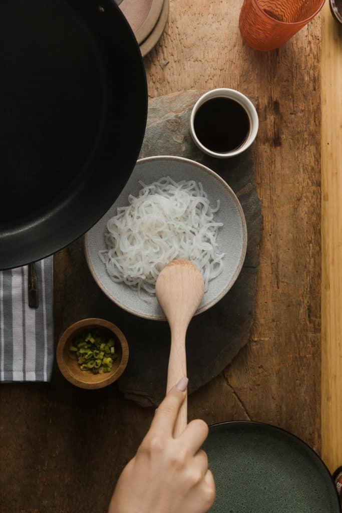 Stirring miracle noodles in a bowl with a wooden spoon