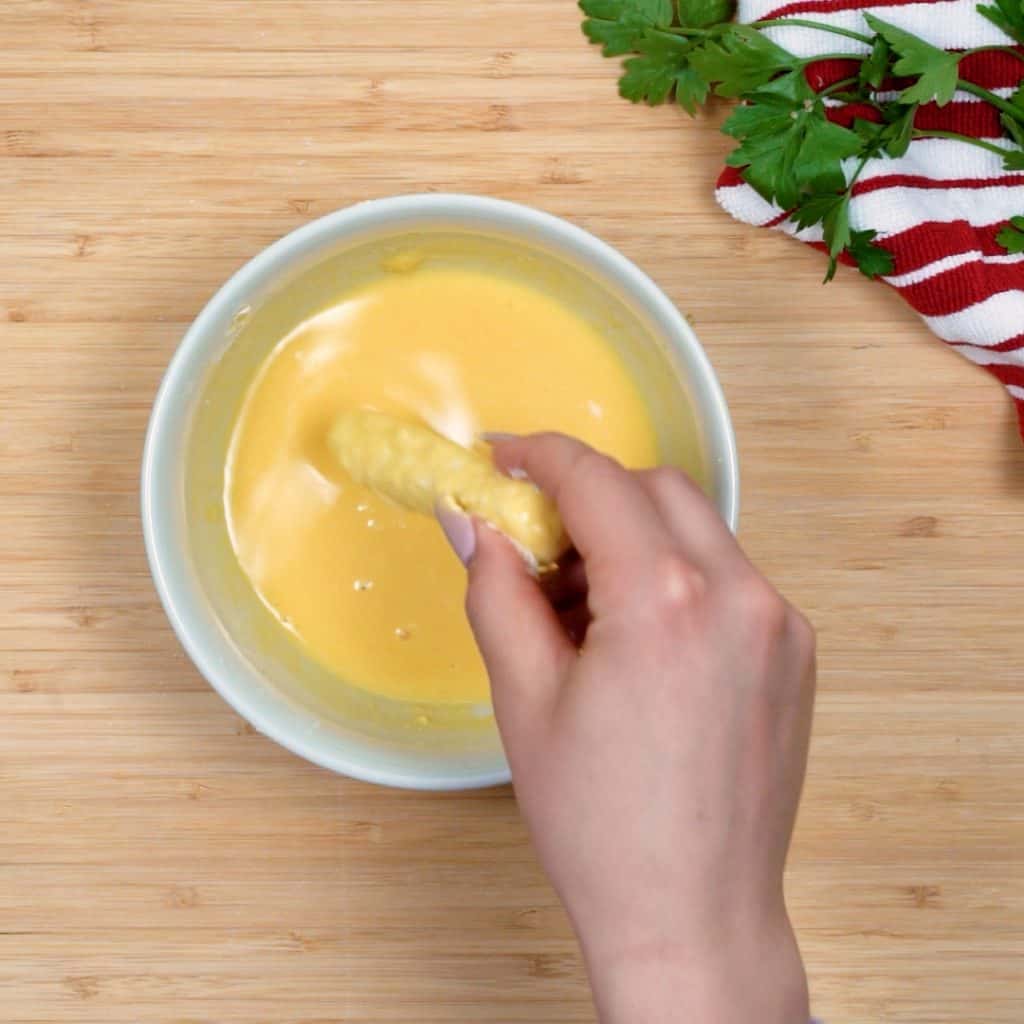 start by dipping cheese sticks in the egg and cream mixture