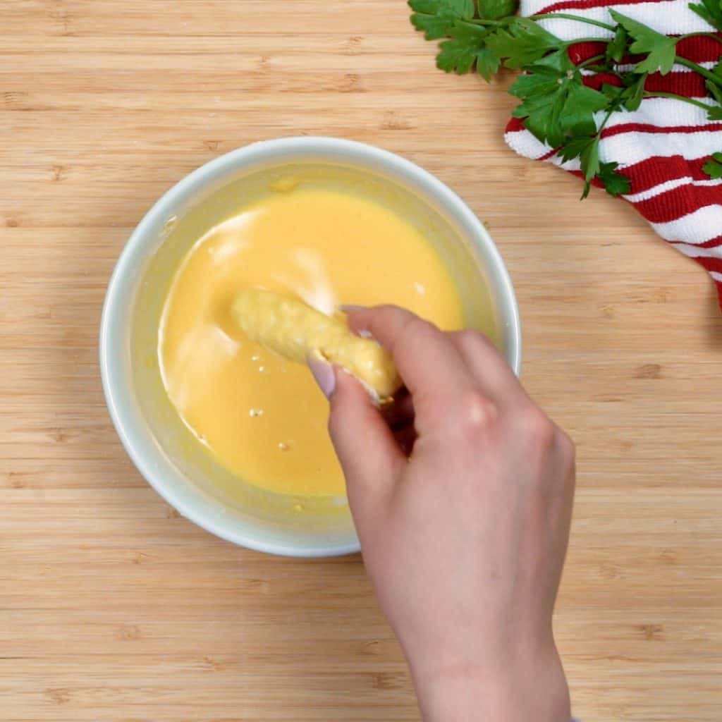 keto mozzarella sticks start by dipping cheese sticks in the egg and cream mixture