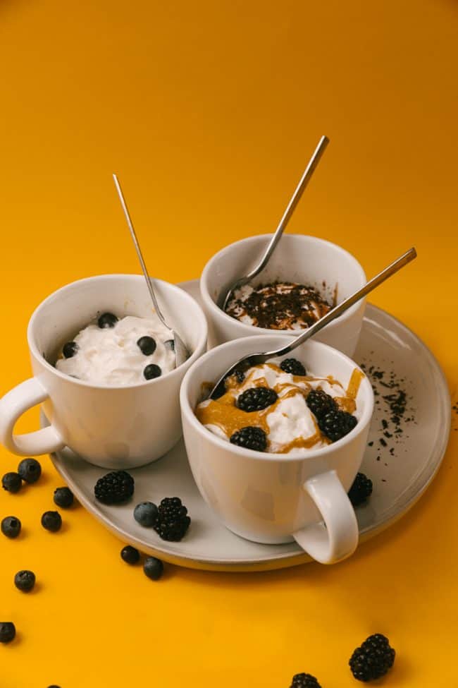 three flavors of keto mug cakes on a plate in coffee mugs