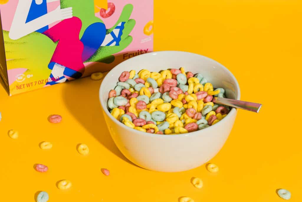 bowl of mutli colored cereal on orange background with a spoon