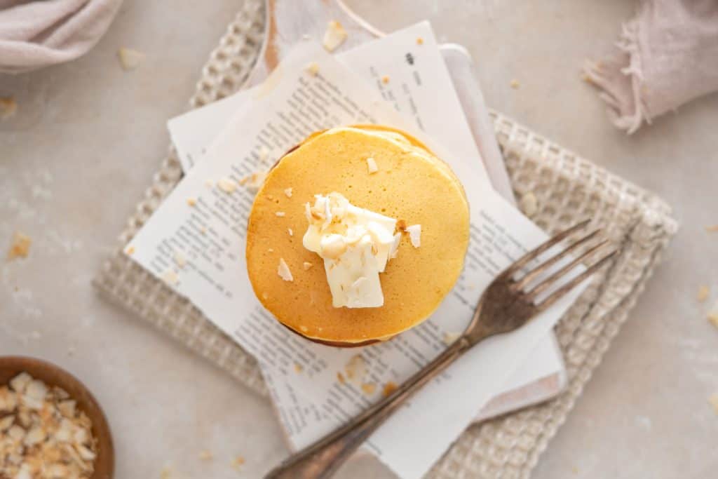 Protein Pancakes A silver for next to a stack of pancakes topped with butter and coconut