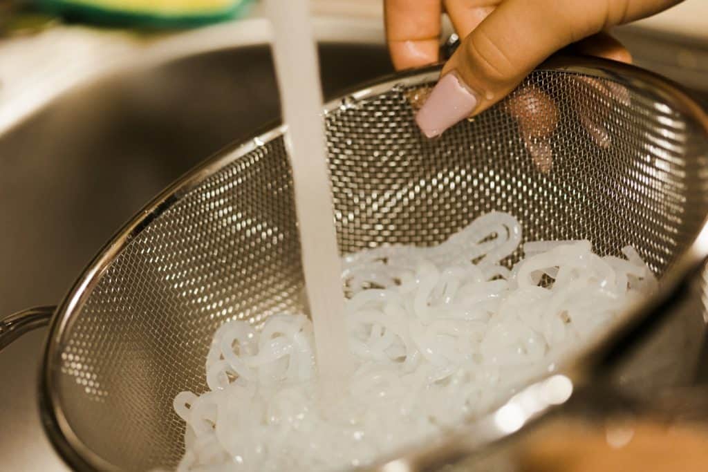 Rinsing miracle noodles in a strainer under running water
