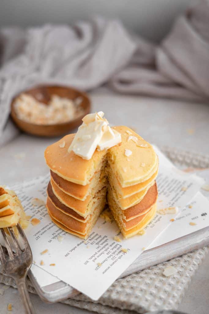 Sliced protein pancakes with a pat of butter and flecks of coconut