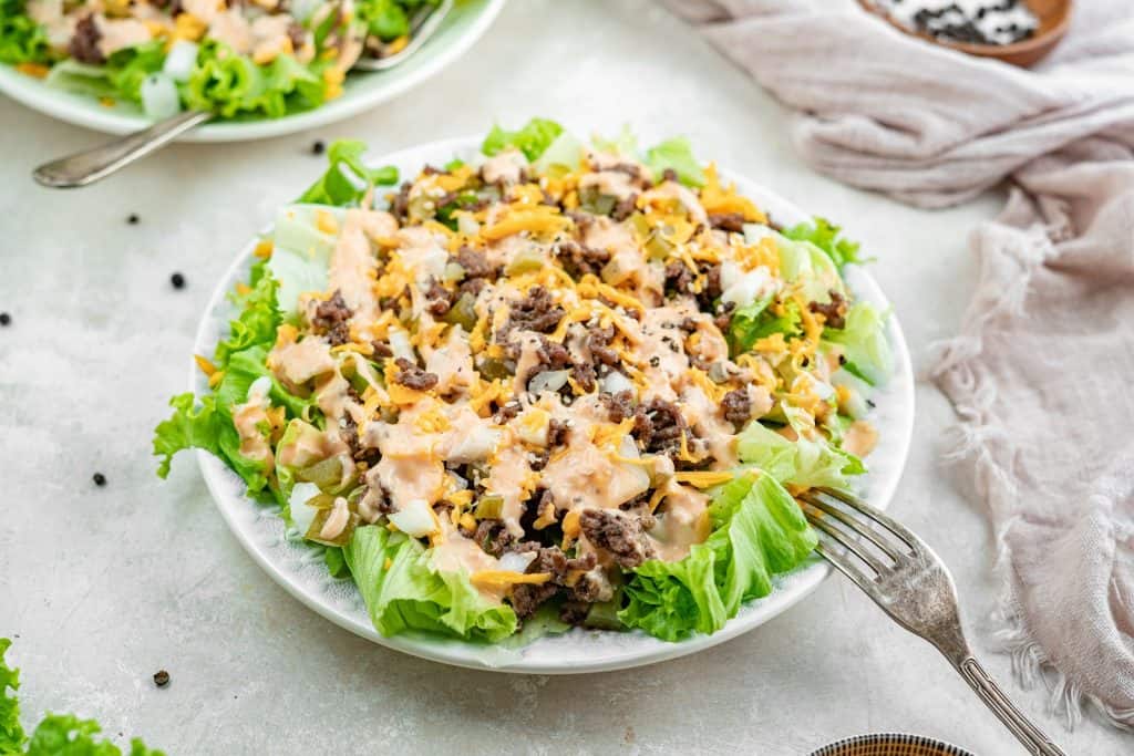 An angled shot of the big mac salad in a white bowl with a fork stuck out of it.