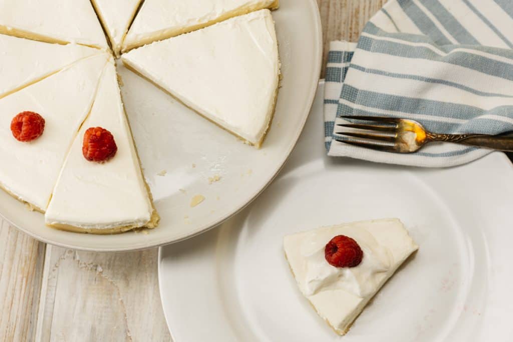 keto no bake cheesecake Overhead shot of Keto No bake cheesecake on a platter with one slice on a plate to the side