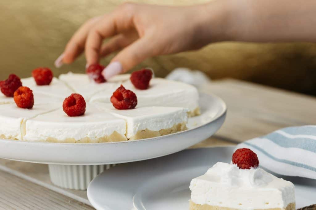 Angled shot of berries being placed onto a keto cheesecake