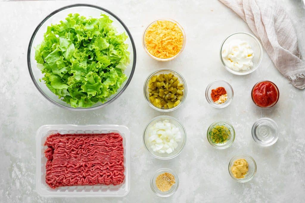 All the ingredients for a big mac salad in separate bowls