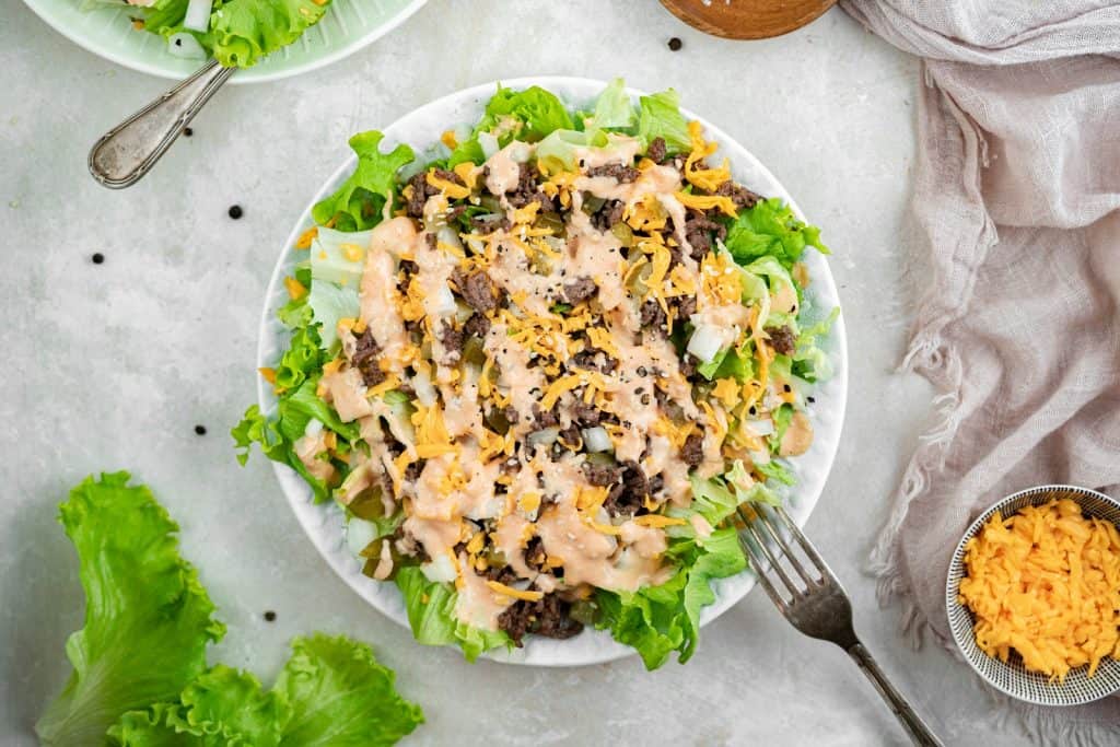 Overhead view of big mac salad in a white bowl with a fork sticking out