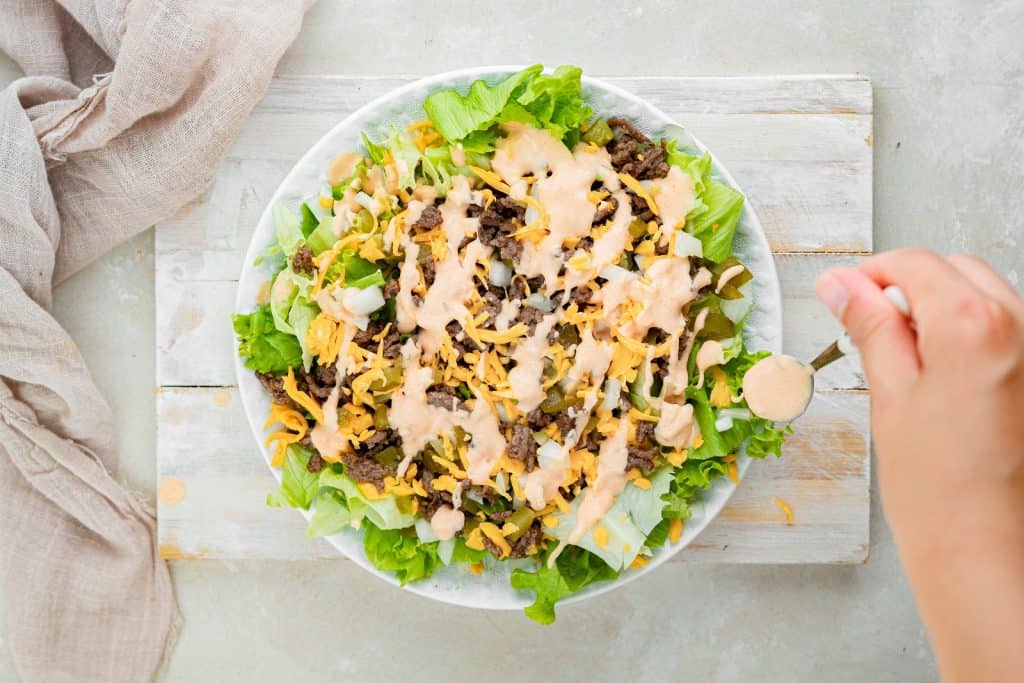 big mac salad Adding sauce with a spoon onto the big mac salad