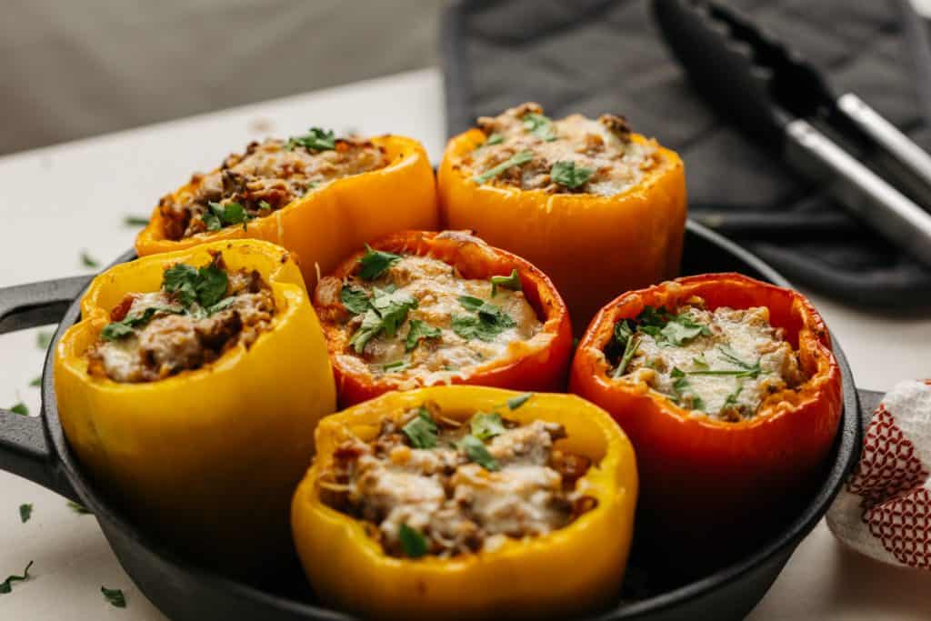 A variety of stuffed bell peppers filling a cast iron pan