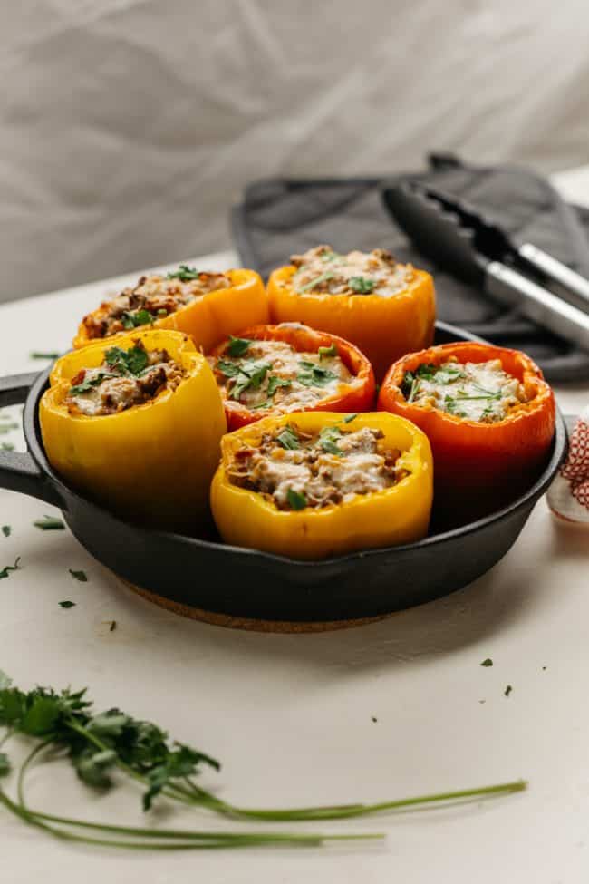Angled shot of a variety of keto stuffed peppers in a cast iron skillet