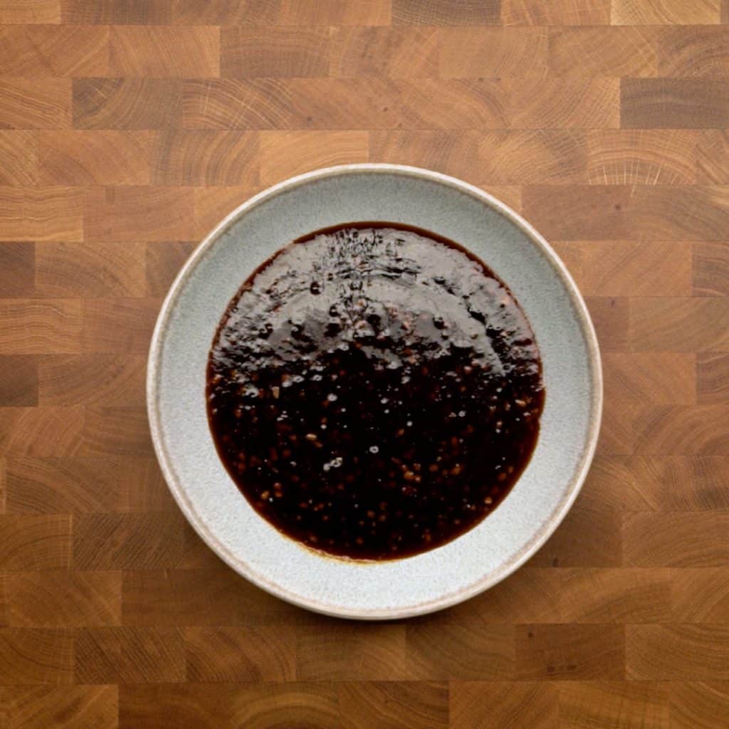 A bowl of teriyaki sauce sitting on a wooden table